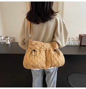 Detail of mustard yellow quilted puffy shoulder bag featuring front drawstring pockets