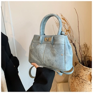 Detail of light blue handbag featuring metal twist lock and stud ornaments with top handles