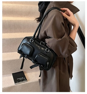 Detail of black glossy leather bag featuring silk bows and dual front zipper pockets