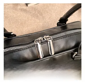 Detailed close-up of smooth black leather bag featuring silver dual metal zipper heads