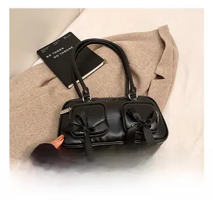 Detail of black faux leather shoulder bag with twin front pockets and satin bows