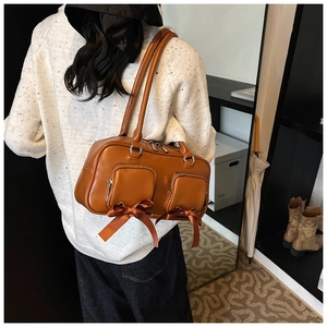 Detail of vintage brown leather underarm bag featuring double pockets and ribbon bows