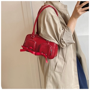 Detail of red vintage underarm bag featuring front zip pockets and satin bows