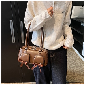 Close-up of brown matte faux leather handbag with zip pockets and satin bows detailing