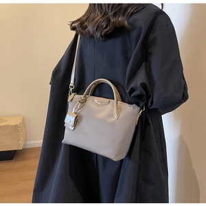 Model wearing a large grey Oxford tote bag with shoulder strap and small pouch