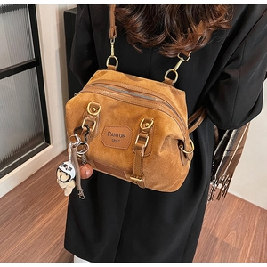 Close-up of brown suede backpack detail with PANTOR SRIES logo and gold metal hardware
