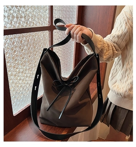 Détail d'un sac cabas en daim marron avec nœud noir et bandoulière réglable en gros plan