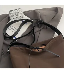 Detail of the brown tote bag featuring black long straps and minimalist drawstring closure