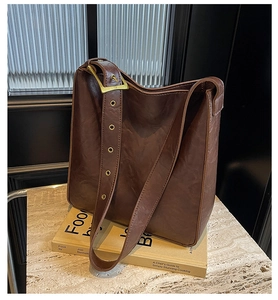 Detailed close-up of dark brown wax leather strap with vintage gold buckle on a tote bag