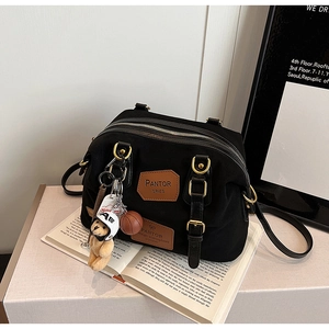 Close-up of black denim tote with leather logo, bear charm and orange basketball detail