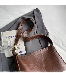 Close-up of vintage brown leather tote bag with adjustable strap and metallic buckle