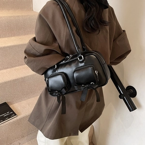 Minimalist black leather shoulder bag with decorative bows and dual front zip pockets