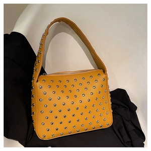 Close-up of yellow punk shoulder bag featuring dense silver rivets and pebble leather texture