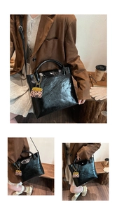 Detailopname van glanzende zwarte tas met mini-bedeltje in luipaardprint uitvoering