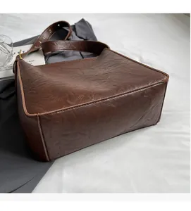 Detail of vintage brown tote bag made of soft pleated faux leather with gold buckles