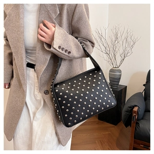Close-up of black rivet handbag with silver studs and pebbled leather texture