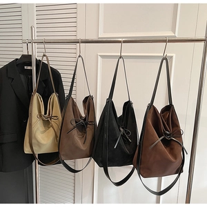Four chic drawstring bucket bags in various colors displayed on a boutique rack