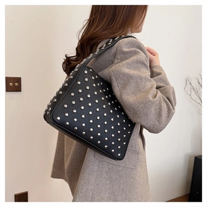 Detail of black studded shoulder bag with silver rivets and textured pebble leather