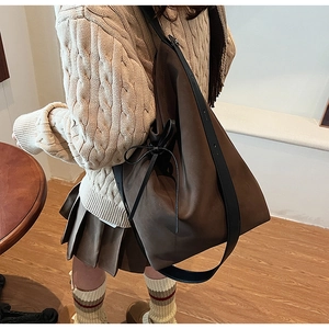 Detail of dark brown suede tote bag with side bow accent and wide shoulder strap