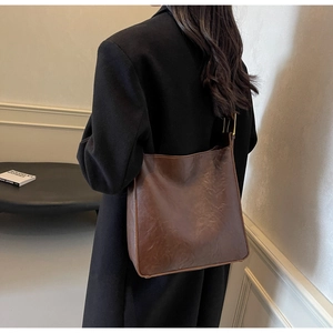 Detail view of vintage dark brown tote bag showing crinkled texture and gold buckles