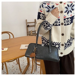 Close-up of matte leather baguette bag with a cute brown bear charm on a woman