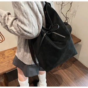 Close-up of black matte tote bag featuring stylish bow tie detail and soft texture