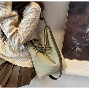 Detail of grey-green bucket bag with leather bow and shoulder strap on model