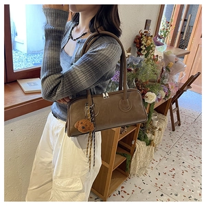 Brown leather baguette shoulder bag with double zipper detail and cute dog charm pendant