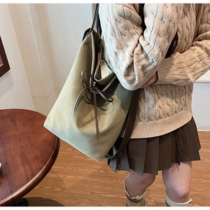 Vue détaillée du sac seau en daim vert Morandi avec un nœud décoratif sur cuir souple