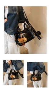Detail of a black Boston bag with glossy finish and cute brown teddy bear charm accessory