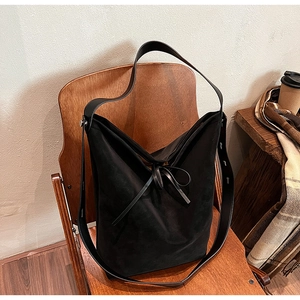 Detail of black matte suede tote bag on a wooden chair showing premium texture and wide strap