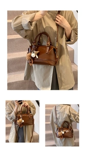 Detail of a brown Boston bag with cute bear charm and adjustable shoulder strap