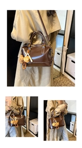 Macro view of brown glossy leather Boston bag with plush bear and strawberry charms