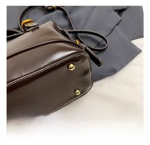 Detail of golden metal feet and contrast stitching on dark brown leather handbag base