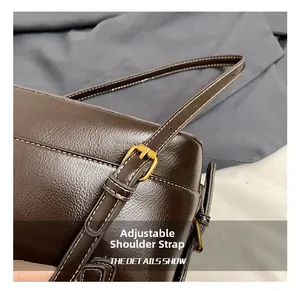Detail of dark brown leather bag showing adjustable shoulder strap with gold buckle
