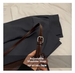 Detailed view of adjustable brown faux leather shoulder strap with silver pin buckle