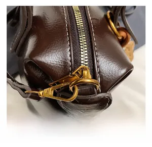 Macro shot of dark brown oil wax leather bag featuring gold zipper and vintage metal hook