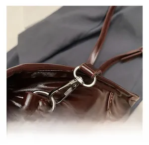 Detail shot of silver metal spring hook and D-ring on dark brown oiled leather bag