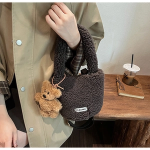 Détail de la texture pelucheuse du sac marron avec petit ours et étiquette de marque