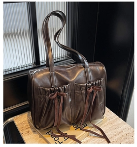 Detailed view of vintage dark brown leather shoulder bag with chic pleated front pockets