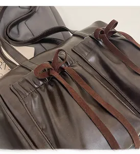 Detail of vintage brown shoulder bag showing pleated opening and suede bow accents