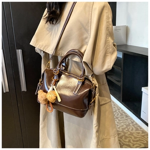 Detail of vintage dark brown Boston bag with teddy bear charm worn on khaki trench coat