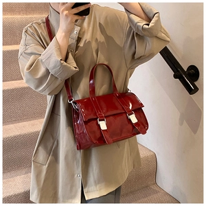 Mirror selfie showing a woman carrying a glossy red patent leather messenger handbag