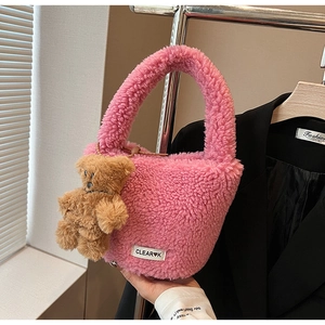 Détail d'un sac seau en peluche rose avec breloque d'ours et cordon de serrage