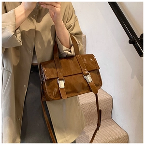 Detailed view of a dark brown vintage messenger bag with glossy oil leather and metal buckles