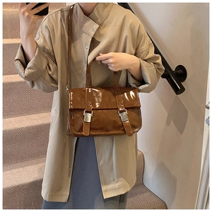 Detail of dark brown glossy leather handbag with silver buckles on a stylish crossbody bag