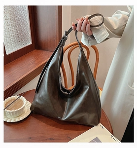 Detail of a large dark brown Hobo bag with brand logo in a cozy cafe setting
