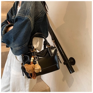 Detalle de bolso Boston en cuero encerado negro con colgante de oso y herrajes dorados