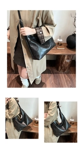 Detail of a black vintage matte leather hobo tote bag worn with a khaki trench coat