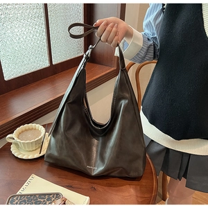 Detail view of large coffee brown hobo tote bag placed on a rustic wooden table